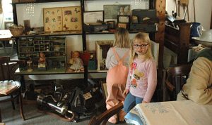 Museumstag 2025 Zwei kleine Mädchen in rosa Shirt und rosa Hose vor einem alten Puppenhaus.
